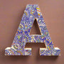 A white Letter A with doodles drawn in Blue and colored in green, orange blue and yellow