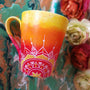 A Gradient hand painted mug from yellow to orange to red , with 1/2 a mandala drawn on the bottom