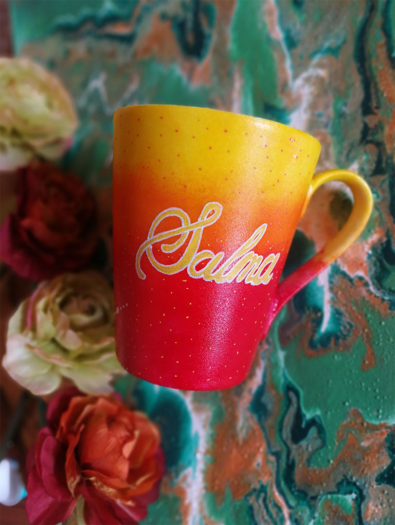 A Gradient hand painted mug from yellow to orange to red , with the name "Salma"