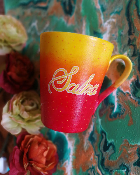 A Gradient hand painted mug from yellow to orange to red , with the name "Salma"