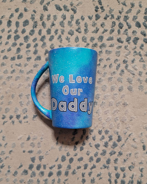 A blue Galaxy hand Painted mug with the sentence "We love our Daddy"