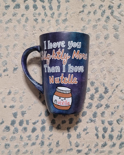 A black sky hand painted mug with the sentence "I love you slightly more than I love Nutella"and a small Nutella jar Painted with a smiley face