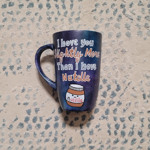 A black sky hand painted mug with the sentence "I love you slightly more than I love Nutella"and a small Nutella jar Painted with a smiley face