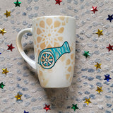 A Shimmery White with gold islamic patterns hand painted mug with a madfa3 painted in black and blue green patterns