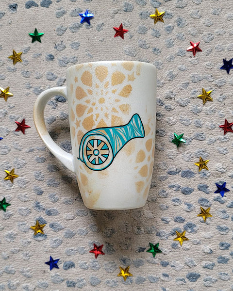 A Shimmery White with gold islamic patterns hand painted mug with a madfa3 painted in black and blue green patterns