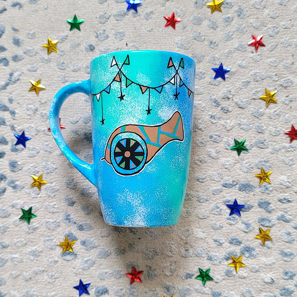 A Blue Green Hand painted mug with decorations hanging from the top all around the mug and a madfa3 painted in black brown, blue and green