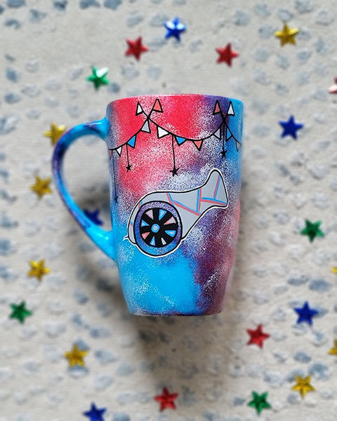 A Blue Red Hand painted mug with decorations hanging from the top all around the mug and a Madfa3 painted in black grey, blue and red