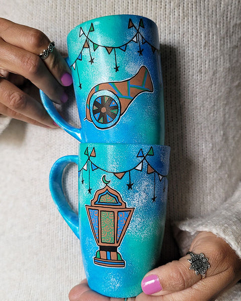 2 hand painted mugs in blue green color with decorations all around the top and one has a fanoos and the other a madfa3