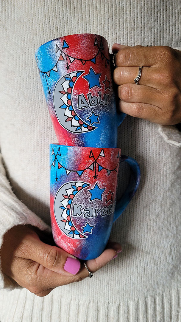 2 hand painted mugs in blue green color with decorations all around the top and one has a moon a name abir the other has a moon and name kareem