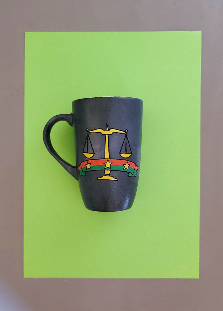 A greyish hand apinted mug with the Egyptian prosecution logo on it