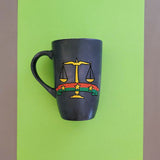 A greyish hand apinted mug with the Egyptian prosecution logo on it