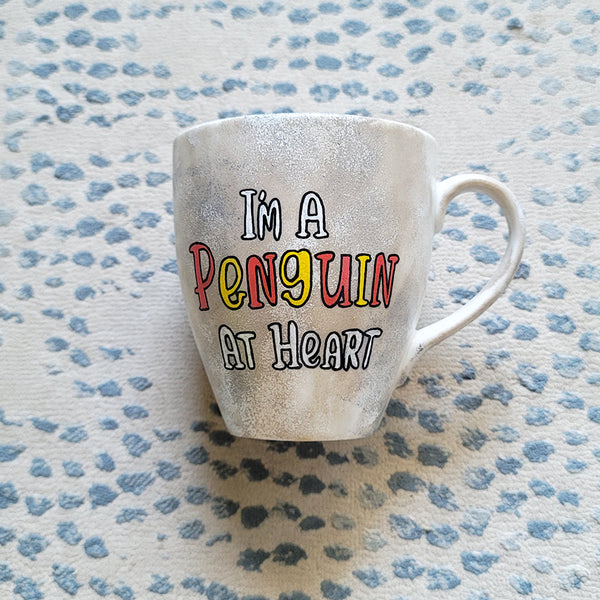 A Taupe hand painted mug with the words "I'm a penguin at heart"