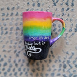 A Mug with the top half painted in rainbow and the bottom in dark galaxy, with the words on the dark galaxy 