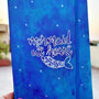 A blue hand painted Notebook with the words "Mermaid at heart" with a mermaid tail painted below it