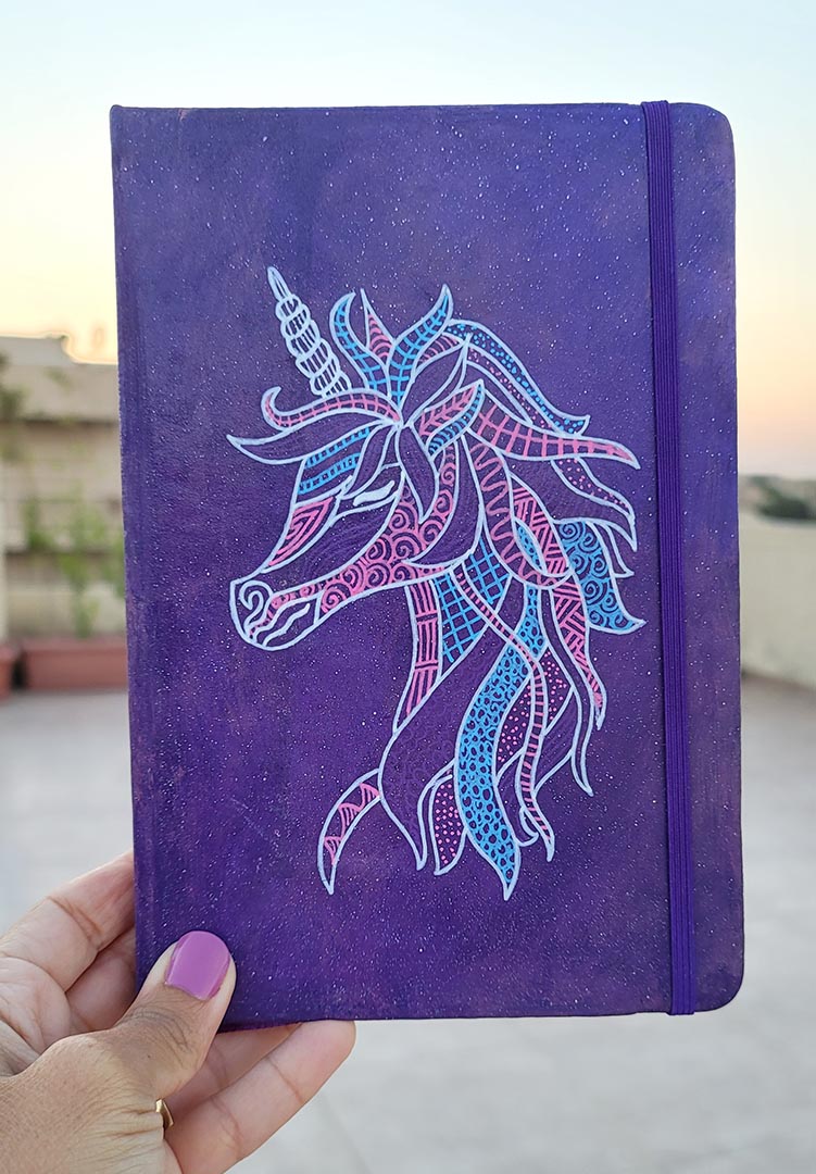 A Purple galaxy notebook  with a unicorn design on it