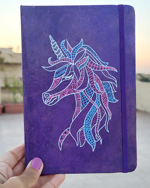 A Purple galaxy notebook  with a unicorn design on it