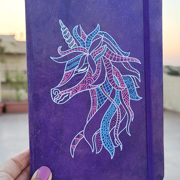 A Purple galaxy notebook  with a unicorn design on it