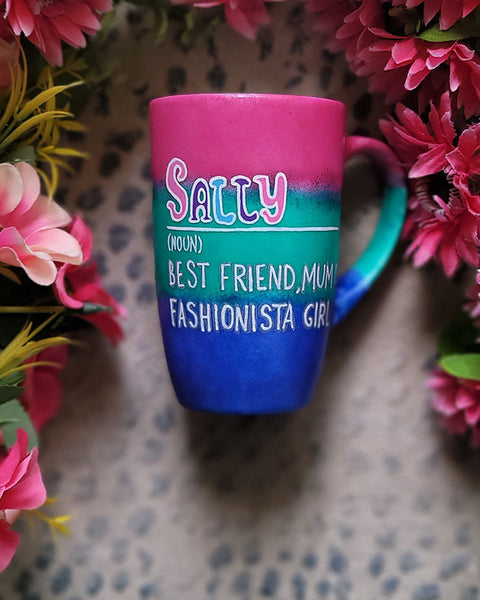 A gradient colored mug (from top fushia then green then blue) with the name sally wirten and then a white line underneath it and then the words Noun in brackets and below it "Best friend, Mum, fashionista Girl"