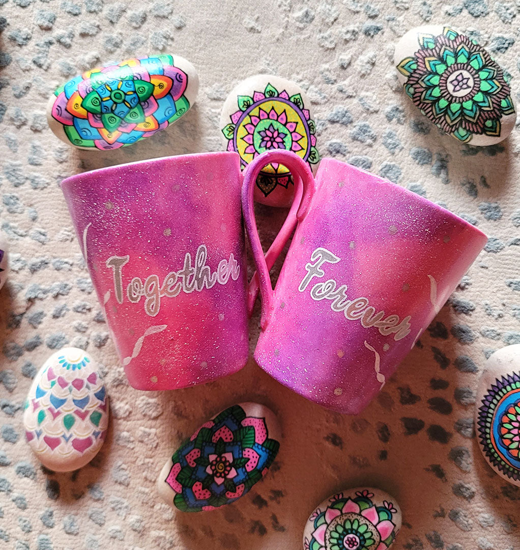 2 hand-painted Pink Galaxy Mugs , one has the word together in silver and white outline and the other has the word forever in silver and white outline