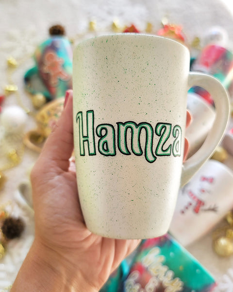 A pearl white hand painted mug with the name "Hamza"