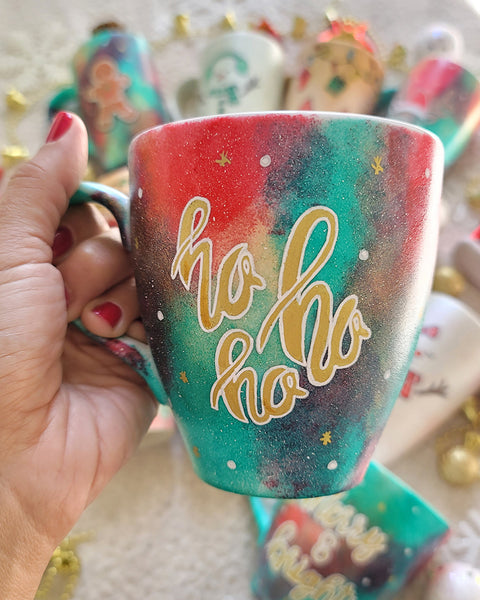 A Christmas galaxy colored hand painted mug with the words "HOHOHO" written gold with white dots and gold stars scattered all over