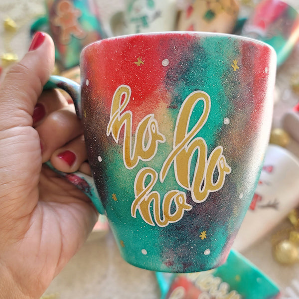 A Christmas galaxy colored hand painted mug with the words "HOHOHO" written gold with white dots and gold stars scattered all over