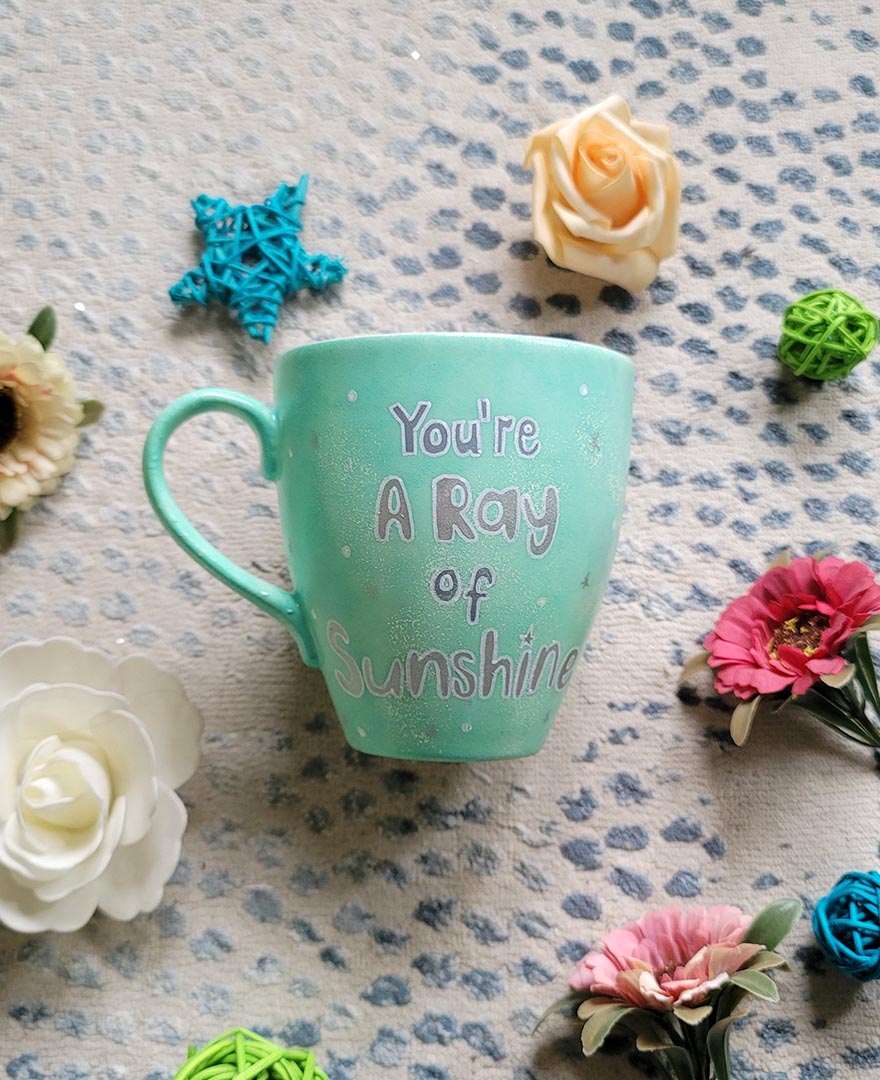 A Mint green handpainted mug with the words "you're a ray of sunshine" in silver