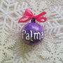 A Purple hand painted ornament with the name "Fatma" written in white outlined with black