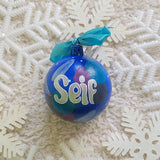 A Colorful hand painted ornament with blue background and colors of blue, black dark purple and silver scattered all over with white dots and the name 