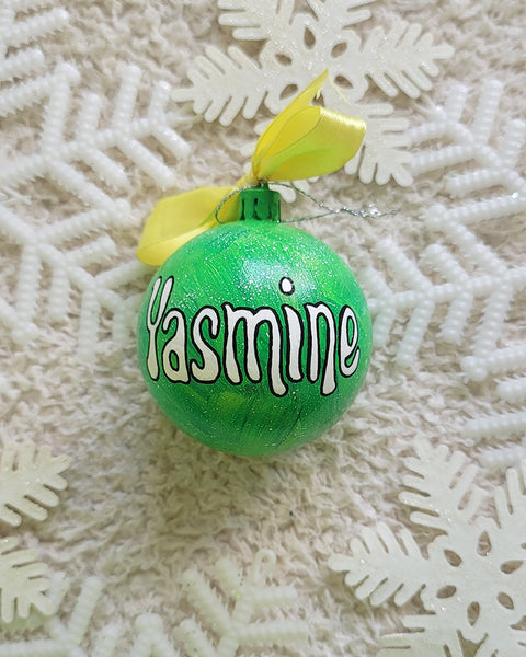 A lime green galaxy hand painted ornament with the name "yasmine" written in white outlined with black