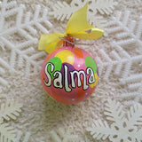 A Colorful hand painted ornament with Pink background and colors of pink, purple, green and yellow scattered all over with white dots and the name 