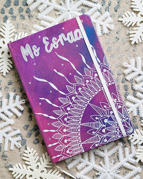 A Pink Galaxy hand painted notebook with a quarter mandala drawn from the corner and the name "Ms. Esraa" written on top