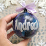 A Black galaxy hand painted ball ornament with the name "Andrew" in silver