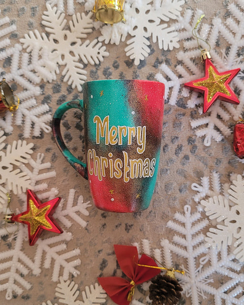 A Christmas galaxy colored hand painted mug with the words "Merry Christmas" written gold with white dots and gold stars scattered all over