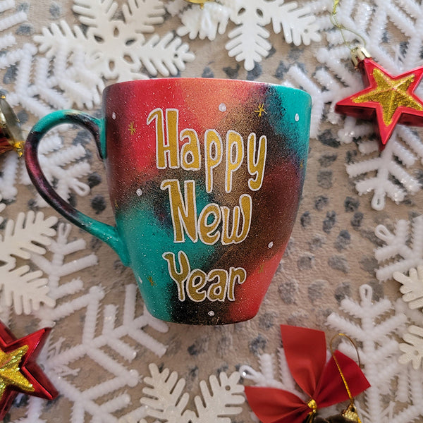 A Christmas galaxy colored hand painted mug with the words "Happy new year" written in gold and white dots and gold stars scattered all over