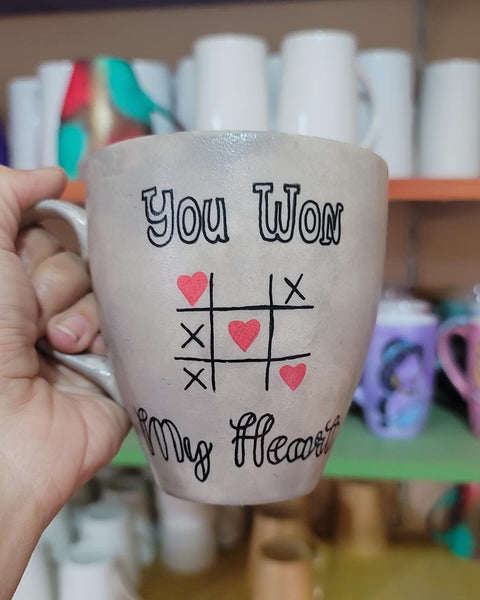 A hand painted Taupe mug with the sentence "you won" and under it an x o chart with hearts instead of o  and three hearts winning the game diagonally, then under it the words "My heart"