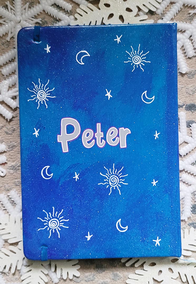 A blue galaxy notebook with small stars and sun patterns scattered all around