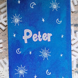 A blue galaxy notebook with small stars and sun patterns scattered all around