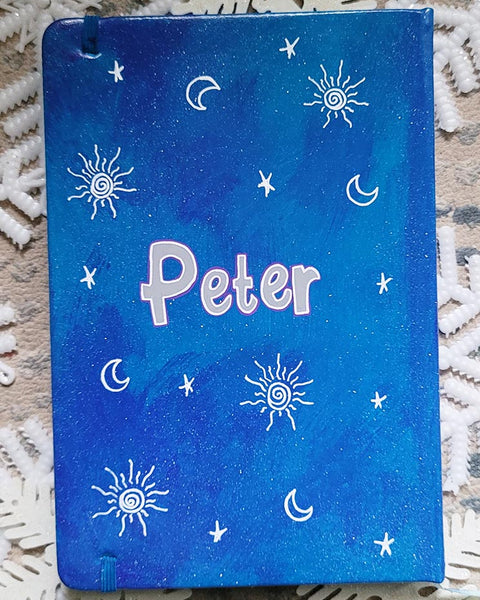 A blue galaxy notebook with small stars and sun patterns scattered all around