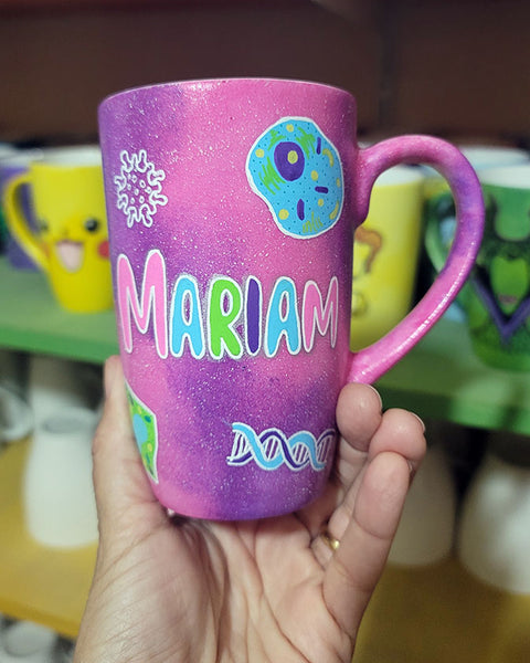 A Pink Galaxy hand painted mug with the name "Mariam" and biology items scattered all over (DNA, Plant cell, microscope...etc.)