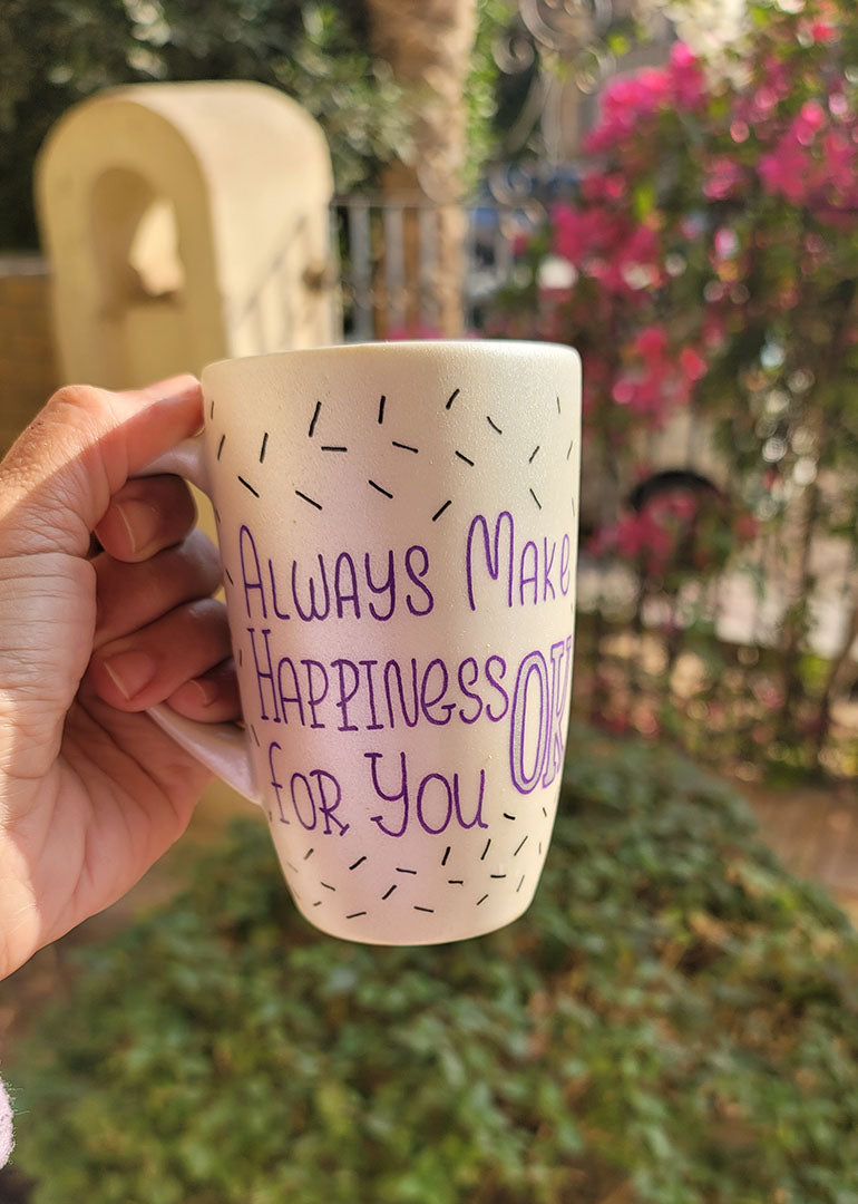 A white pearl hand painted mug with the words "Always Make Happiness ok for you " in purple and black sprinkles scattered all over the mug