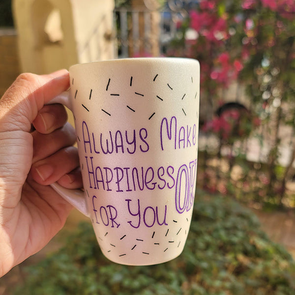 A white pearl hand painted mug with the words "Always Make Happiness ok for you " in purple and black sprinkles scattered all over the mug