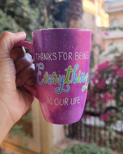 A hand painted pink galaxy mug with the sentence "thanks for being everything in our life"