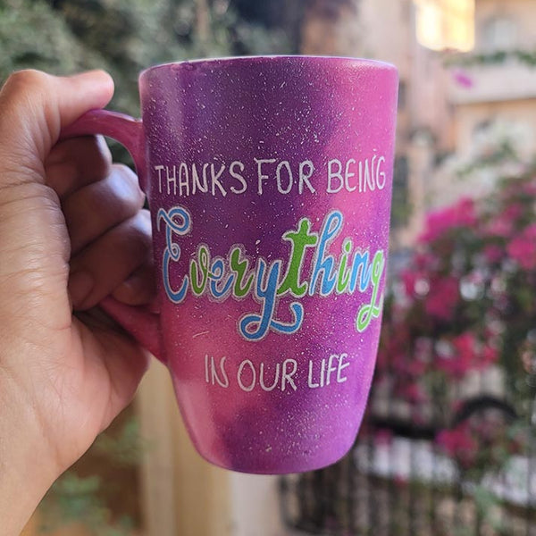 A hand painted pink galaxy mug with the sentence "thanks for being everything in our life"