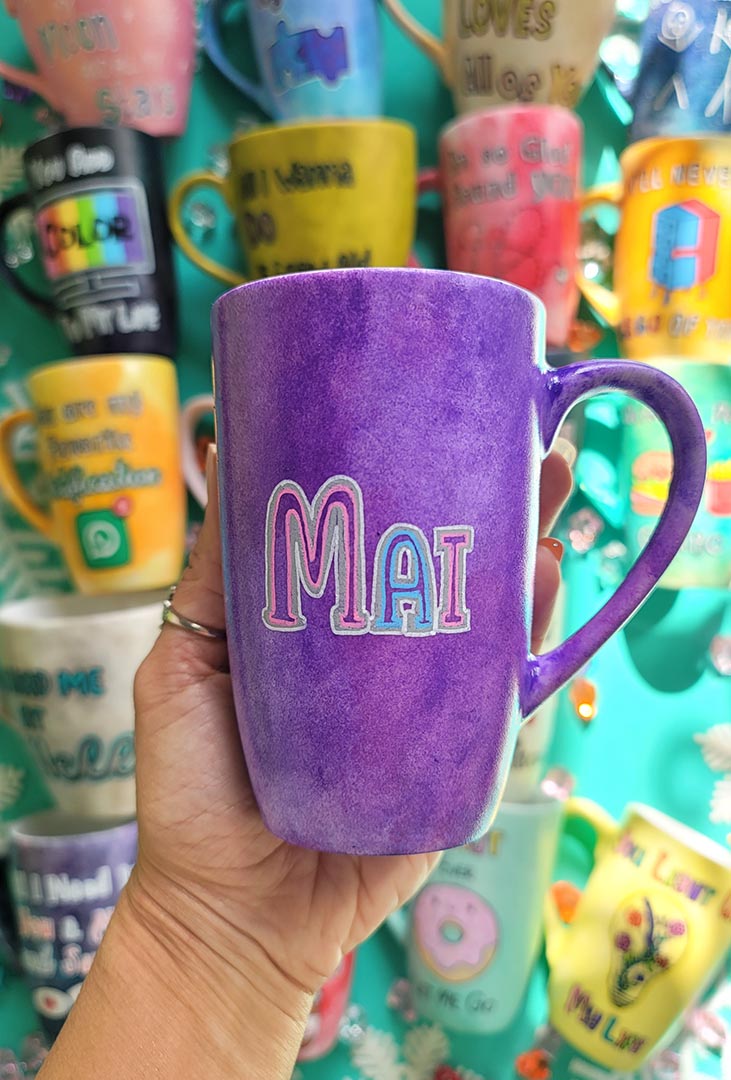 A hand-painted purple galaxy mug with the name "Mai"