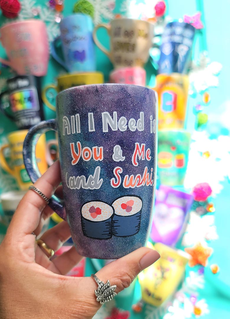 A Hand Painted Black Galaxy Mug with the sentence "All I need is You and ME and Sushi" and 2 sushi rolls drawn below it