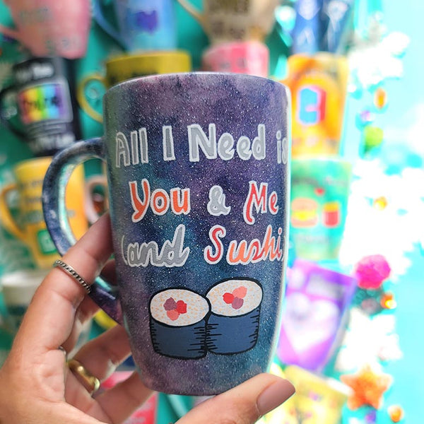 A Hand Painted Black Galaxy Mug with the sentence "All I need is You and ME and Sushi" and 2 sushi rolls drawn below it