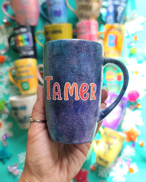 A Hand Painted Black Galaxy Mug with the name "Tamer"