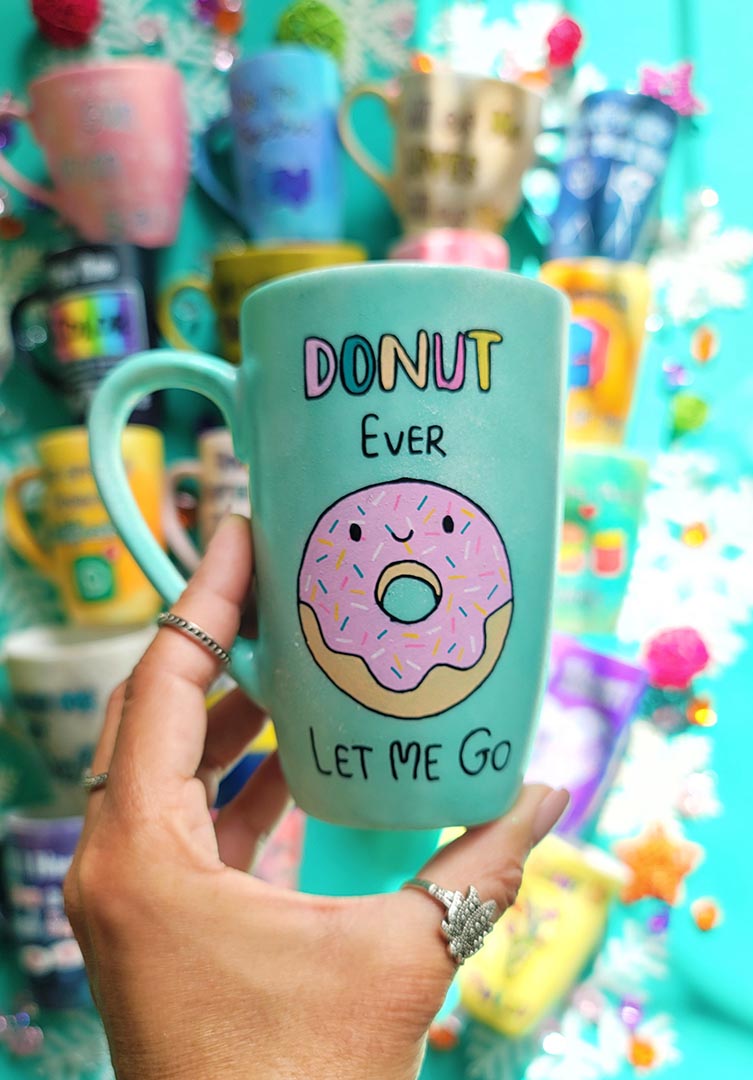 A Pastel green Hand-painted mug with the words "DONUT ever" and then below it a donut painted with pink frosting and sprinkles and a small smiley face. then below it the words "let me go"