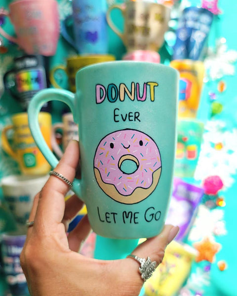 A Pastel green Hand-painted mug with the words "DONUT ever" and then below it a donut painted with pink frosting and sprinkles and a small smiley face. then below it the words "let me go"